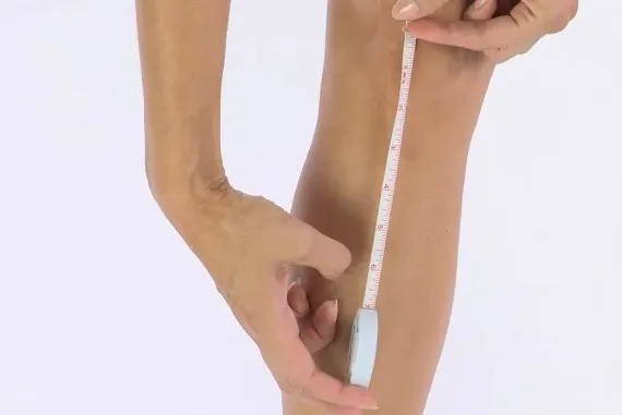 she is measuring her knee using a measuring tape